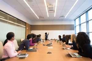 Safeguarding Training Group of people around a large desk watching someone present on a large whiteboard